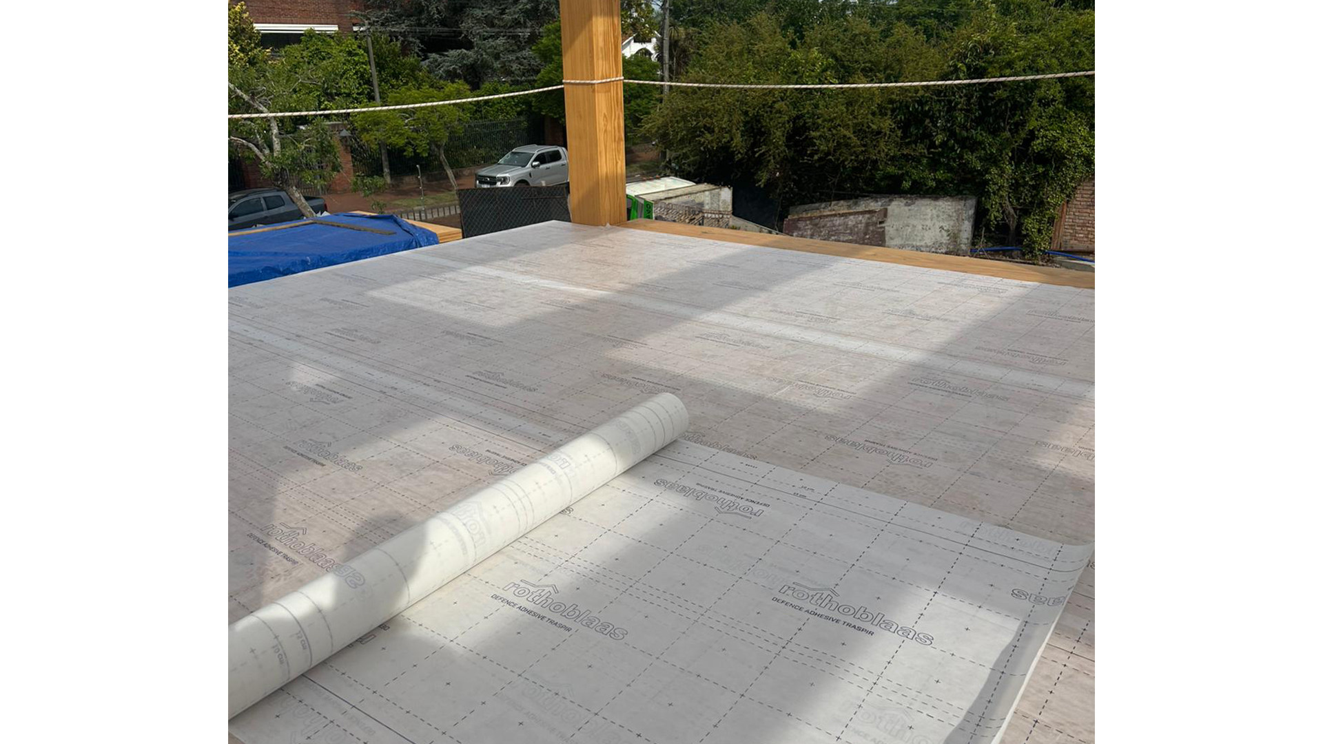 CLT floor with self-adhesive breathable membrane partially installed during mass timber construction for timber protection on site