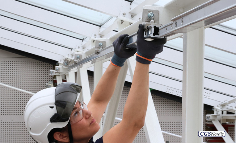 Interior view of a glazed building atrium with white steel roof trusses equipped with H-RAIL rope access system, installed by CGS Nordic for safe building maintenance.