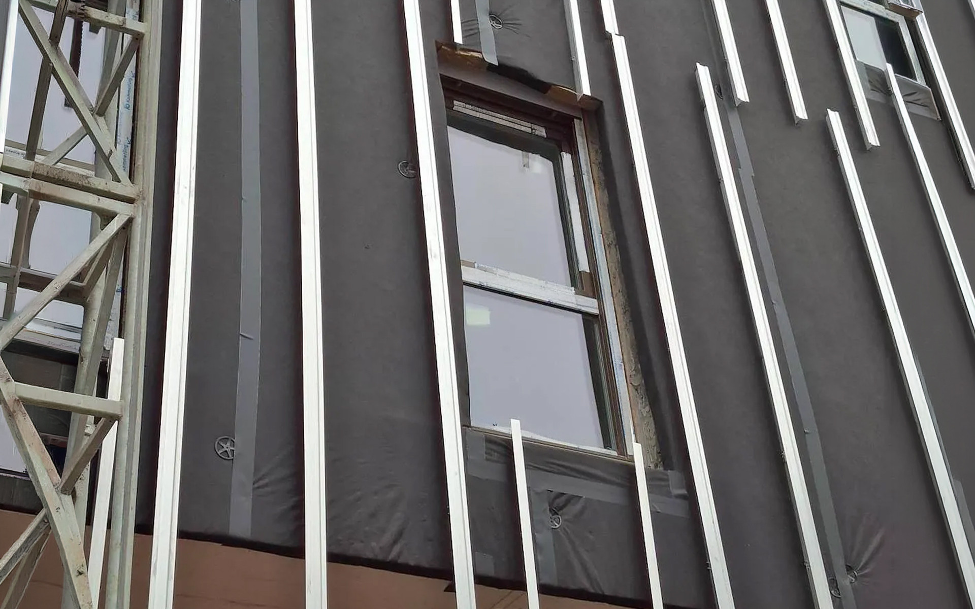 Ventilated façade under construction with breathable membrane and aluminum substructure for building envelope protection 